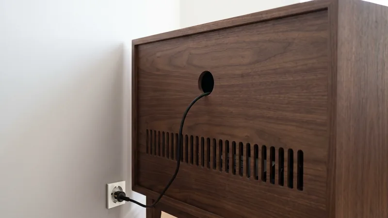 Trasera de un mueble preparado para encastrar una chimenea de vapor: un taladro para el cable y una fila de ranuras de ventilación abajo